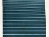 a cat sitting on a window sill in front of a blue roller door