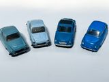 quatre petites voitures sont alignées sur une surface blanche