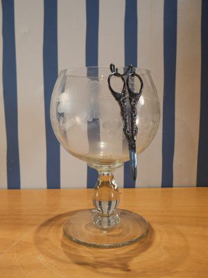 un verre contenant une paire de ciseaux, posé sur une table