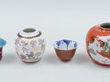 three vases and two cups sitting next to each other