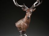 une sculpture en bronze représentant un cerf avec des bois sur la tête