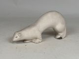 une petite figurine d'ours polaire blanc posée sur une surface blanche