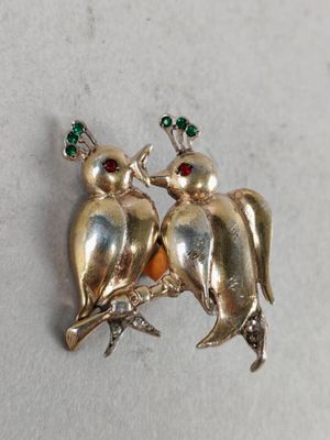 two birds sitting on a tree branch with green crystals in their beaks