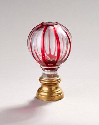 une boule en verre rayée de rouge et de blanc posée sur un socle doré