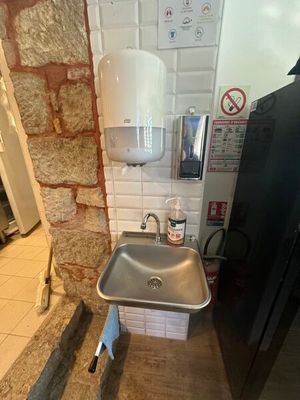 un lavabo dans un coin de la salle de bains, avec une serviette accrochée au mur
