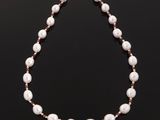a white pearl and ruby beaded necklace on a black background