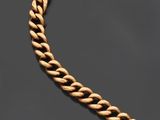 un bracelet en chaîne d'or muni d'un fermoir, posé sur un fond noir