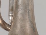 a silver vase with a silver handle on a table