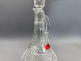 a clear glass bottle with a red stopper on it