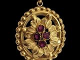 an image of a close up of a gold pendant with a flower