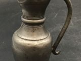 a small silver pitcher sitting on a table