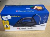 une boîte contenant un fer à repasser à vapeur Ultra Pro de Russell Hobbs posée sur une table