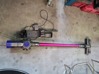 a pink and blue vacuum on the floor next to a bike