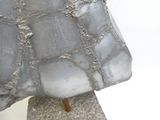 une sculpture représentant un rocher posé sur un socle, sur lequel repose un morceau de glace