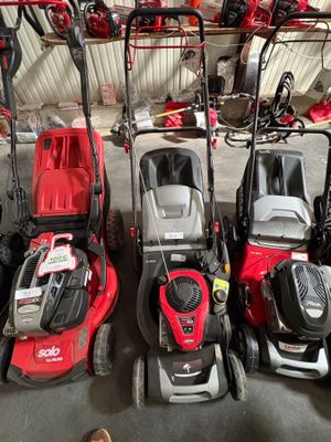Plusieurs tondeuses à gazon sont alignées dans un garage