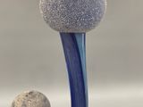 a close up of a blue vase with two balls on it