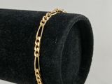 un gros plan d'un bracelet à chaîne en or posé sur un présentoir à bagues noir