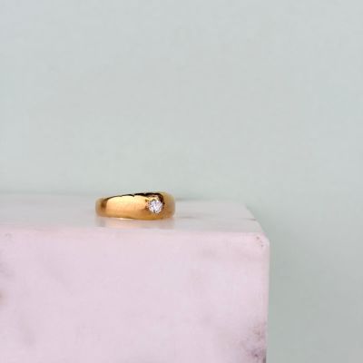 a close up of a gold ring with a diamond on top of a marble block