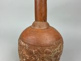 a brown vase with a wooden handle on a white surface