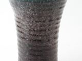 a close up of a blue and black vase on a white surface