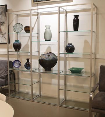 a glass display case with vases on it in the corner of a room