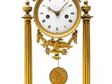 a gold clock with a white face on a stand
