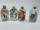 four glass snuff bottles with asian paintings on them on a white surface