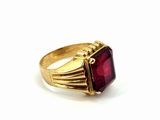 a close up of a gold ring with a red stone