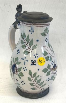 un pichet blanc orné de motifs bleus et verts