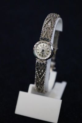 a close up of a watch on a white stand on a black background