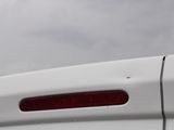 the rear end of a white car with a red tail light