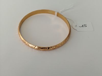 a close up of a gold bracelet on a white surface