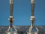 une paire de bougeoirs anciens en argent posés sur une table en marbre, sur fond bleu