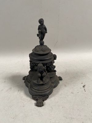 un bougeoir ancien en fonte surmonté d'une figurine