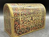 un coffret richement décoré, doré et rouge, posé sur une table