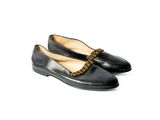 une paire de chaussures noires avec une chaîne sur la pointe