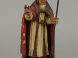 figurine représentant un homme vêtu d'une robe rouge, tenant un bâton et un chien