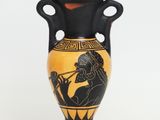 a black and yellow vase with a picture of a man playing a flute