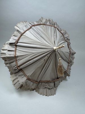 un parapluie en papier auquel est suspendu un pompon
