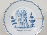 une vieille assiette bleue et blanche sur laquelle est représenté un ange