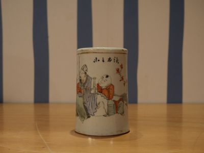 une petite tasse posée sur une table, avec en arrière-plan un mur rayé de bleu et de blanc