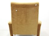 beige velvet lounge chair with metal legs and arm rests against a white wall