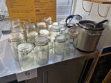 many jars on a table with a pot on top of it