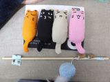 four cats that are sitting on top of a knitting needle