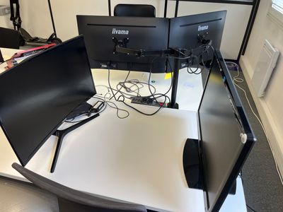two computer monitors sitting on top of a white desk