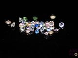 un gros plan sur un assortiment de diamants de différentes couleurs posés sur une surface noire