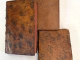 trois vieux livres posés les uns à côté des autres sur une table blanche