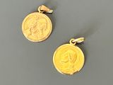 deux pendentifs en forme de pièces d'or, sur lesquels figurent respectivement le visage d'une femme et celui d'un homme