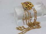 a gold necklace with a skull on it sitting on a clear box