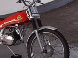 a red motorcycle parked in a parking lot next to a wall